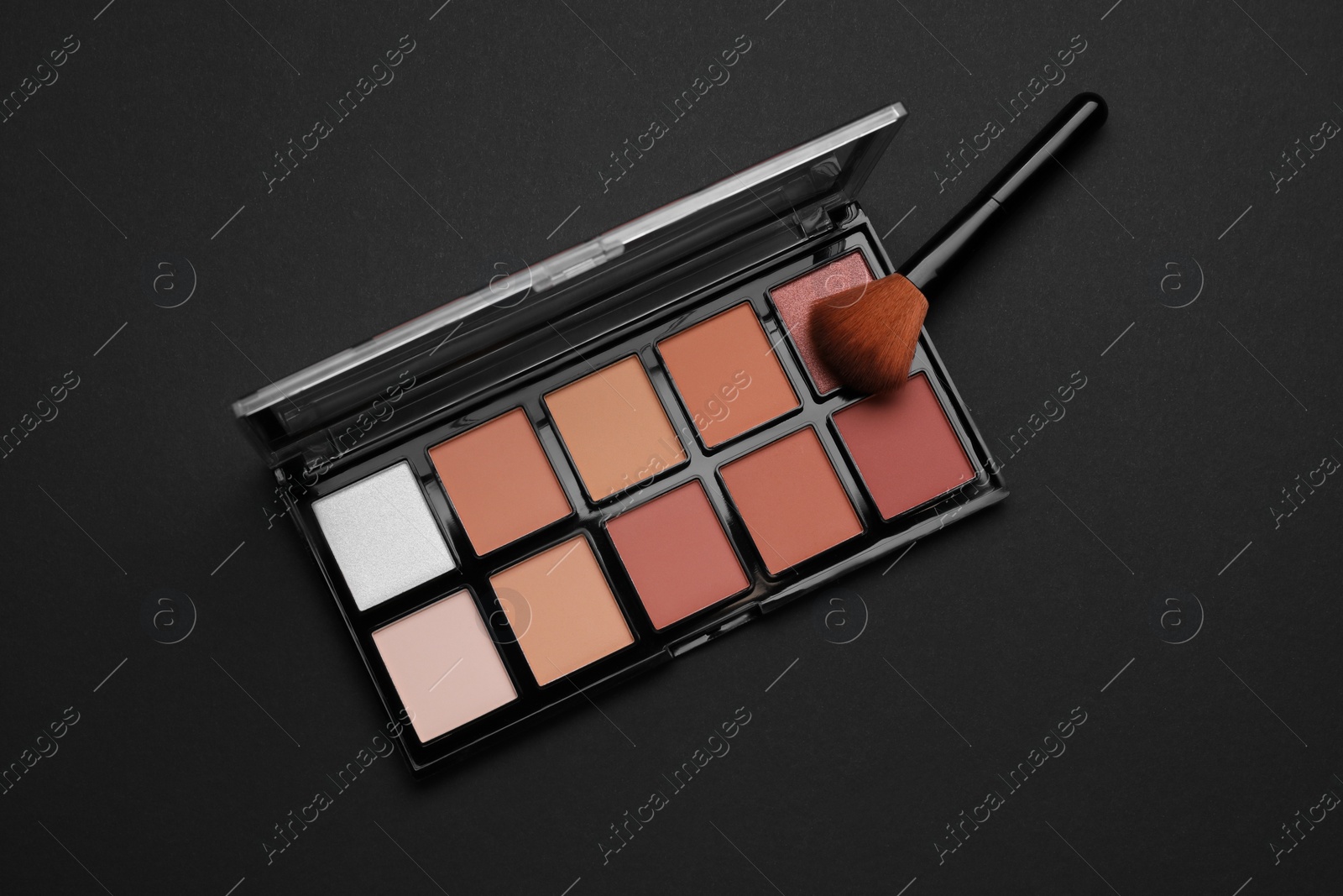 Photo of Contouring palette and brush on black background, top view. Professional cosmetic product