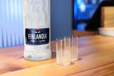 MYKOLAIV, UKRAINE - SEPTEMBER 23, 2019: Finlandia vodka and shot glasses on wooden bar counter