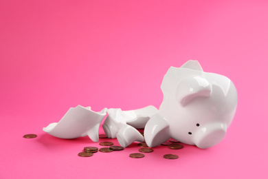 Photo of Broken piggy bank with coins on pink background