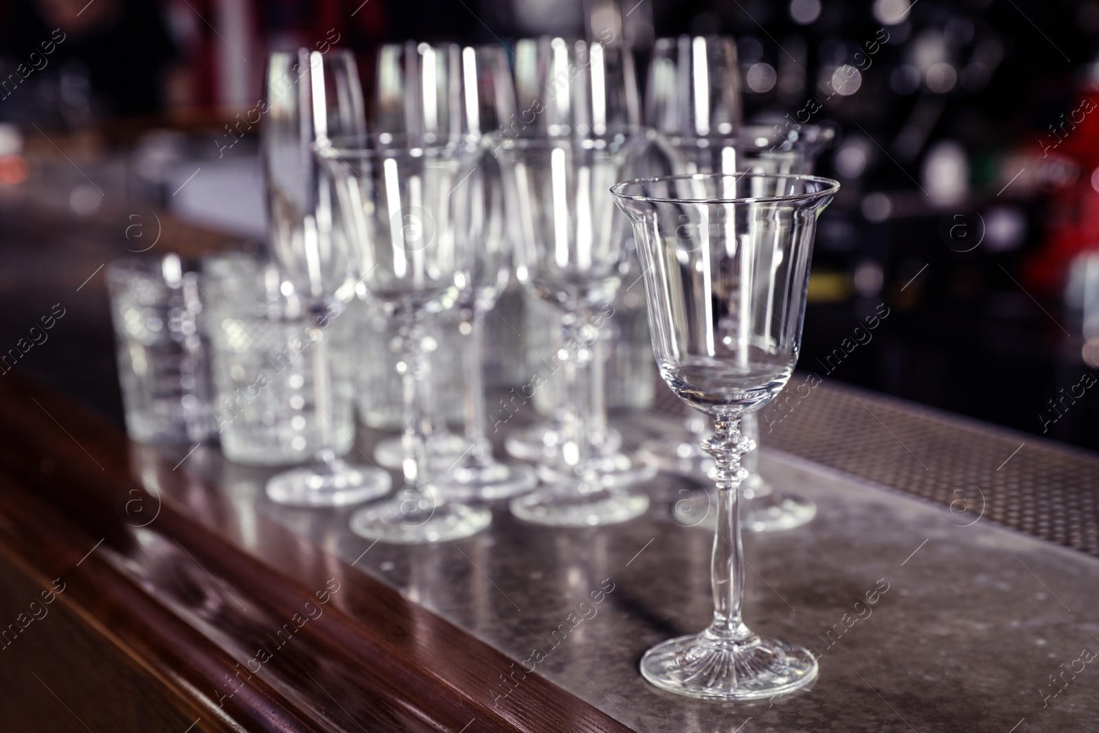 Photo of Different empty clean glasses on counter in bar