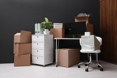 Photo of Cardboard boxes and packed belongings in office. Moving day