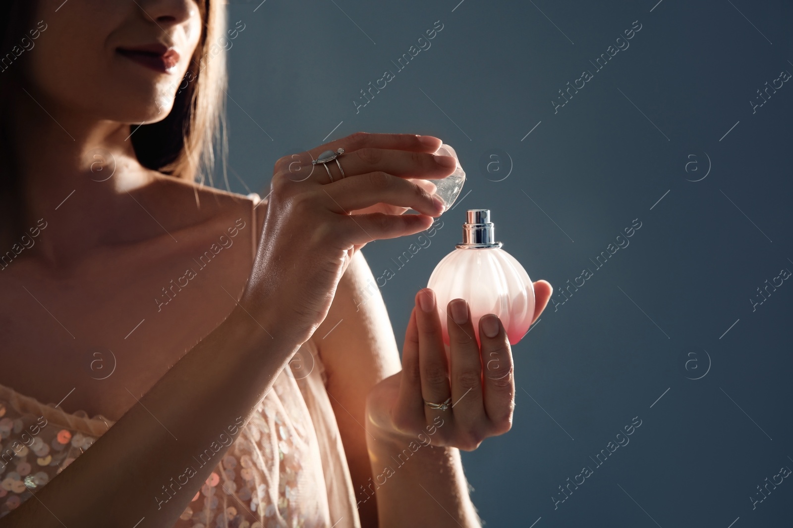 Photo of Young woman with perfume bottle on gray background, closeup. Space for text