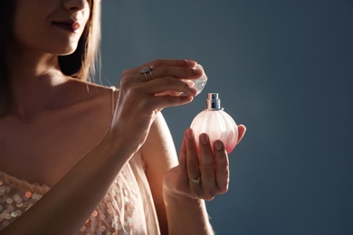 Young woman with perfume bottle on gray background, closeup. Space for text