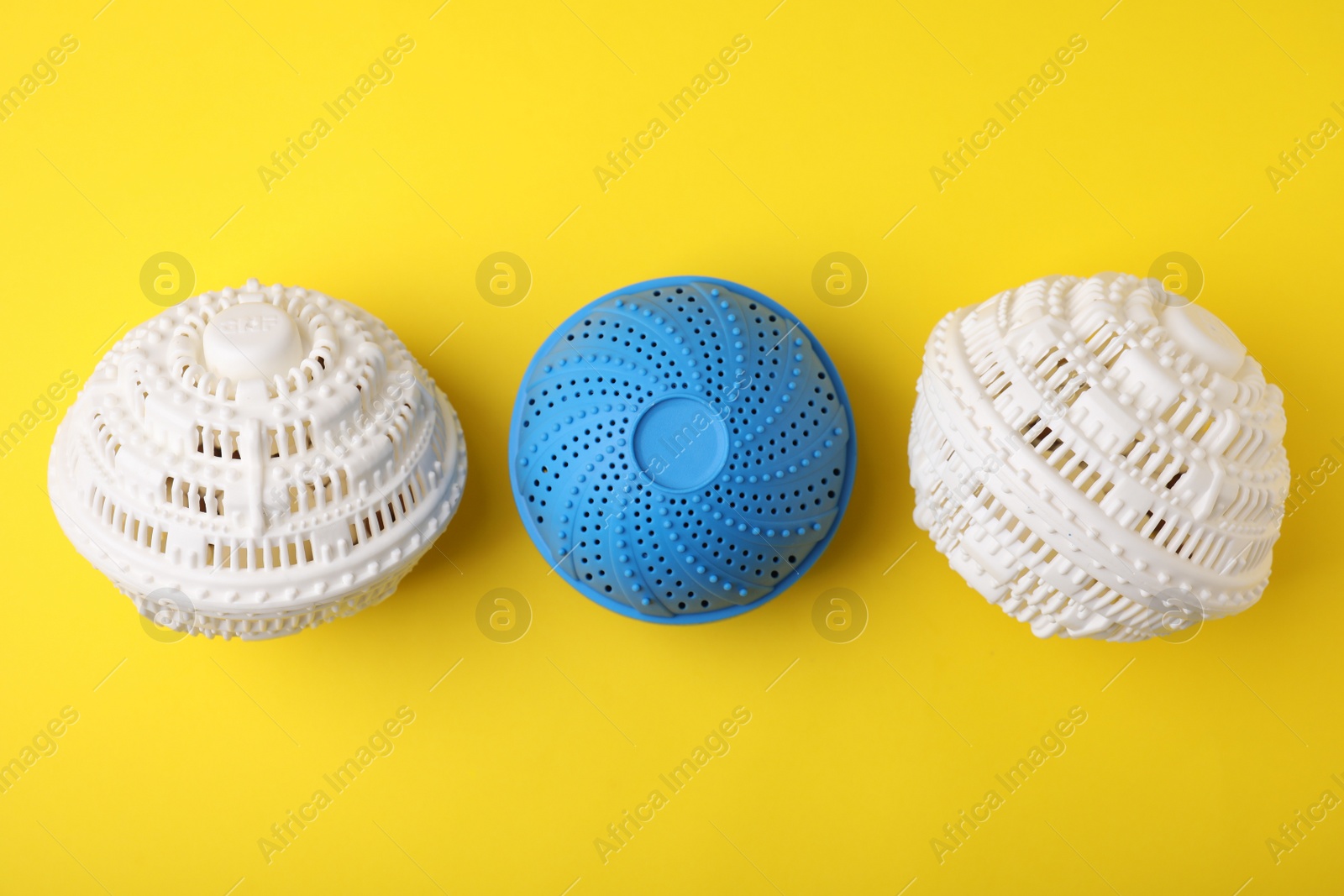 Photo of Dryer balls for washing machine on yellow background, flat lay