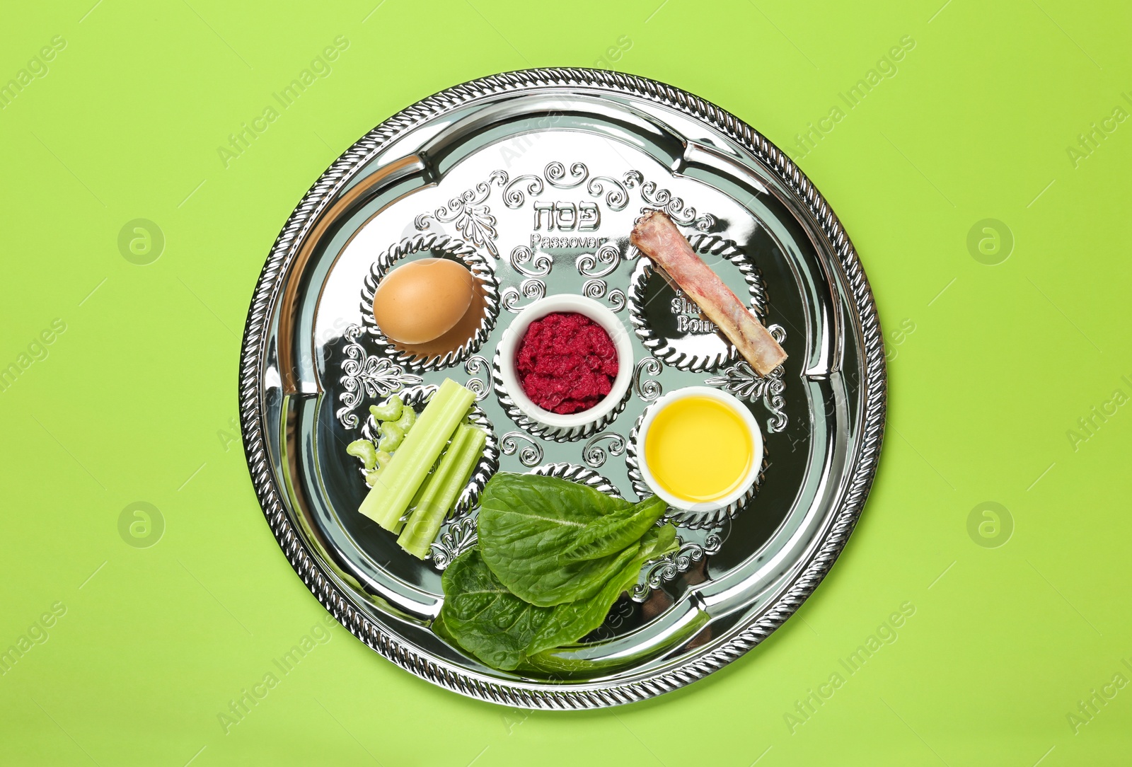 Photo of Passover Seder plate (keara) with symbolic meal on green background, top view. Pesah celebration