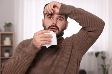Photo of Sick man with tissue at home. Cold symptoms