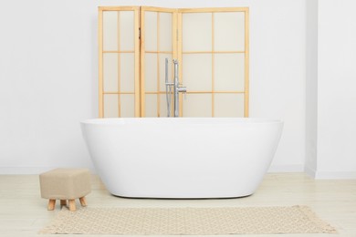 Photo of Beautiful white tub and ottoman in bathroom. Interior design