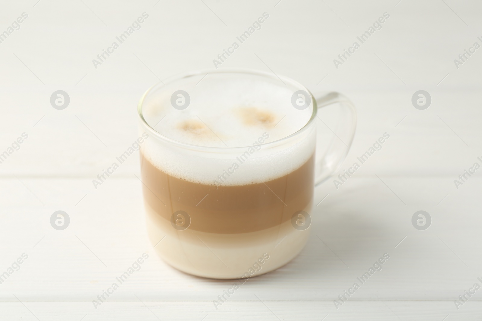 Photo of Aromatic coffee in glass cup on white wooden table, closeup