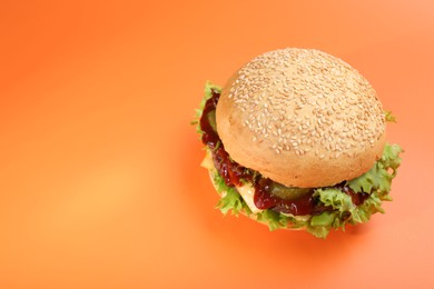 Photo of Delicious cheeseburger on coral background, above view. Space for text