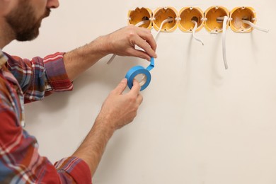 Electrician fixing wires with insulating tape indoors, closeup