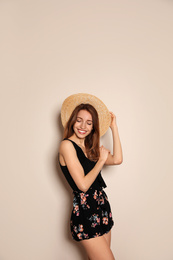 Photo of Young woman wearing floral print shorts and straw hat on beige background