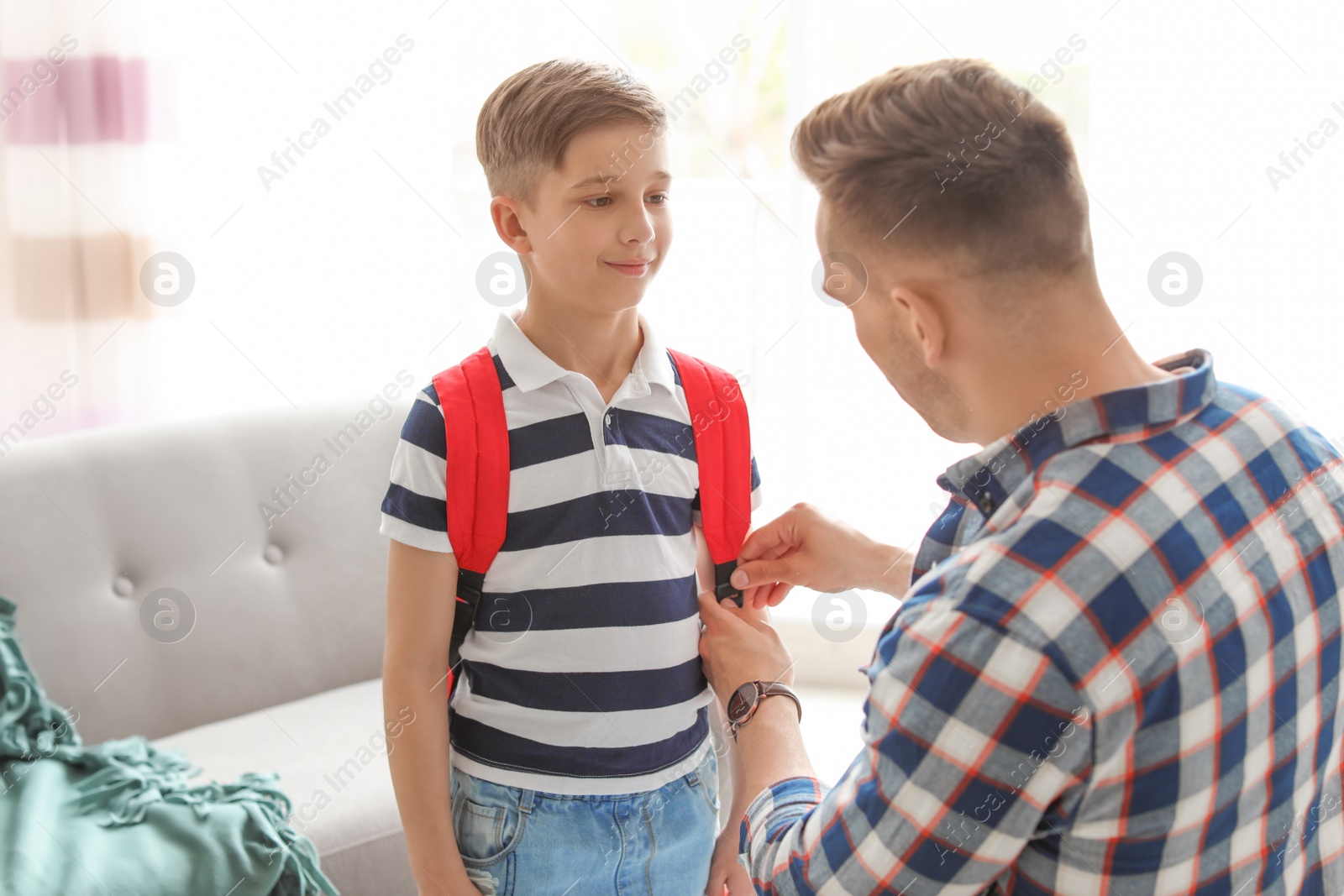 Photo of Young man helping his little child get ready for school at home