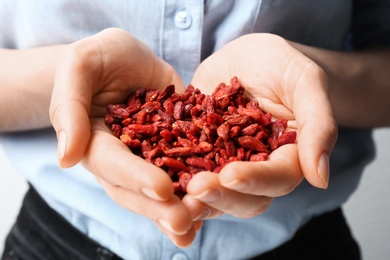 Photo of Woman holding red dried goji berries, closeup