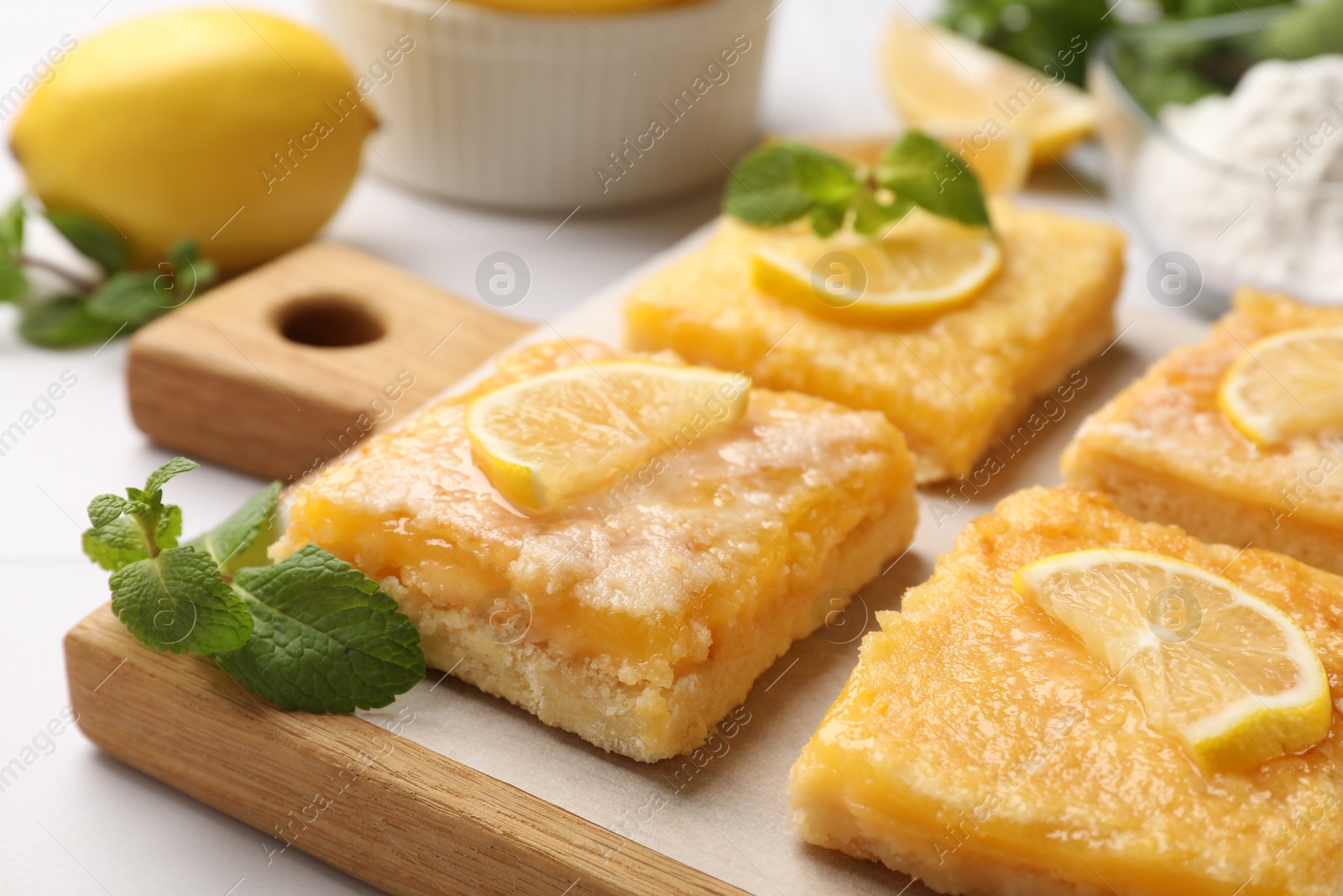 Photo of Tasty lemon bars and mint on white table, closeup