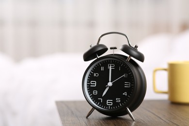 Black alarm clock on wooden table indoors. Space for text