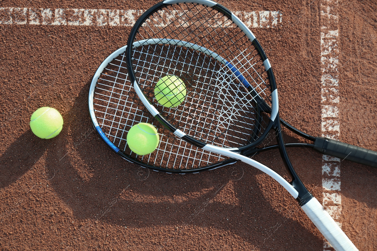 Photo of Tennis balls and rackets on clay court, flat lay