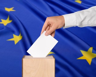 Image of Man putting his vote into ballot box against flag of Europe, closeup