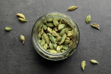 Photo of Jar with dry cardamom pods on dark grey table, top view