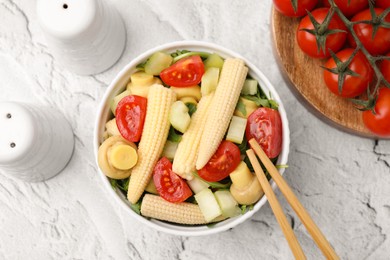 Tasty baby corn with vegetables and champignons on grey textured table, flat lay