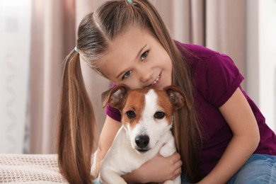 Photo of Cute girl hugging her dog indoors. Adorable pet