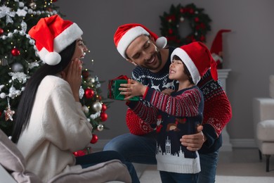 Father with his cute son presenting gift to mother at home. Christmas celebration