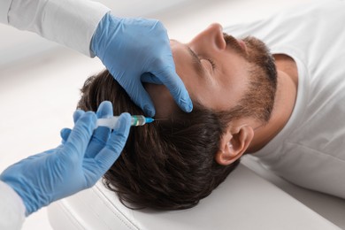 Trichologist giving injection to patient in clinic, closeup