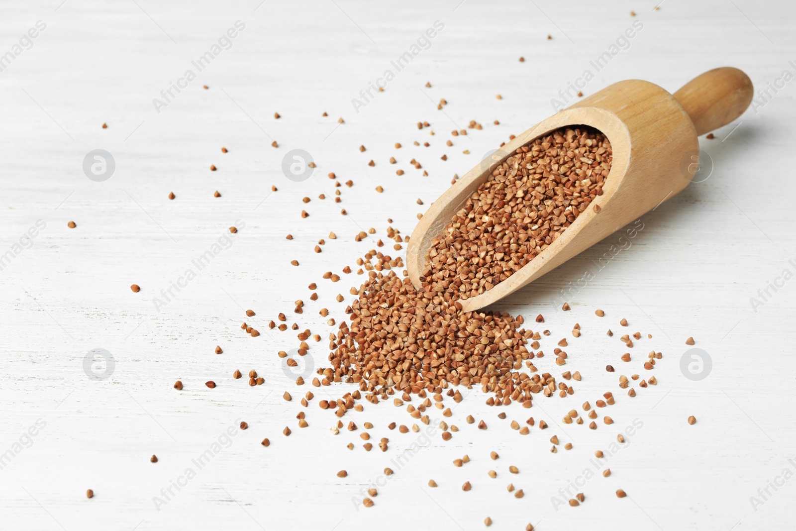 Photo of Uncooked buckwheat grains on white wooden table