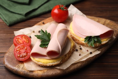 Photo of Delicious sandwiches with boiled sausage, cheese and tomatoes on wooden table, closeup