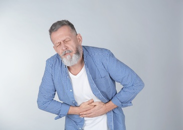 Man suffering from abdominal pain on light background