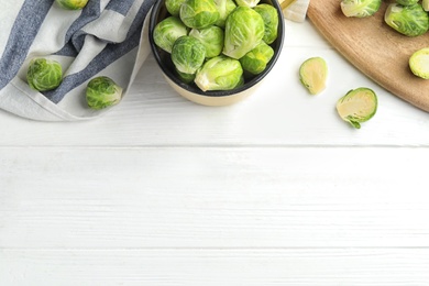 Fresh Brussels sprouts on white wooden table, flat lay. Space for text