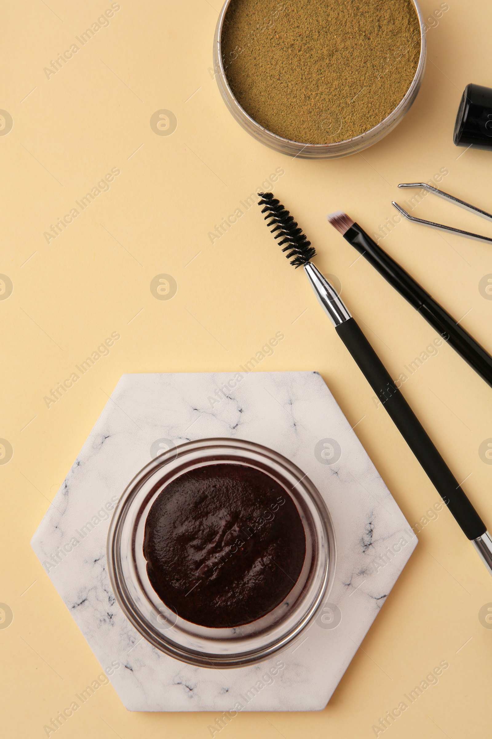 Photo of Flat lay composition with eyebrow henna and tools on beige background