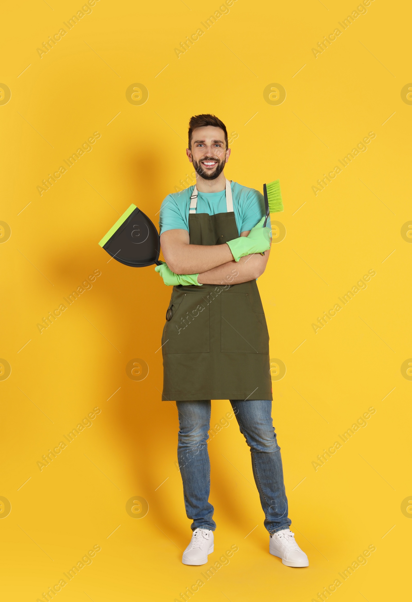 Photo of Man with brush and dustpan on orange background