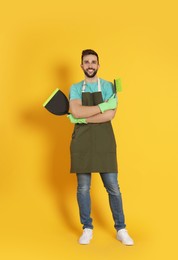 Photo of Man with brush and dustpan on orange background