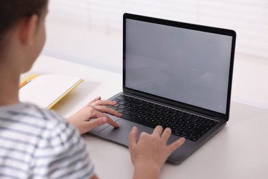 Photo of E-learning. Girl using laptop during online lesson at table indoors, closeup