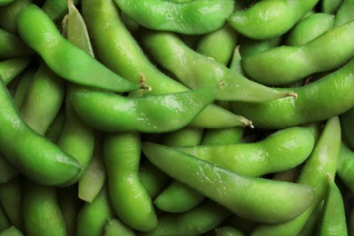 Many green edamame beans in pods as background, closeup