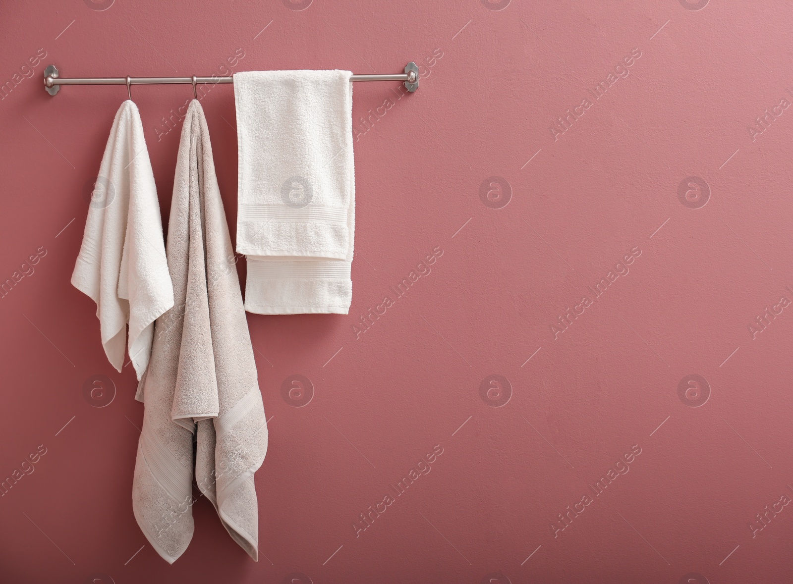 Photo of Hanger with clean towels on color wall