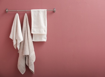 Photo of Hanger with clean towels on color wall