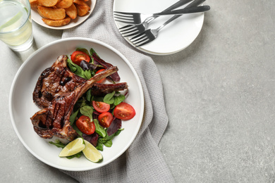 Photo of Delicious grilled ribs served on light grey table, flat lay. Space for text