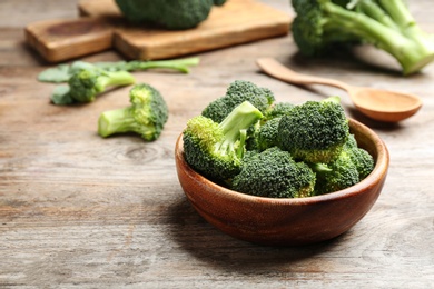 Photo of Bowl of fresh broccoli on wooden table. Space for text