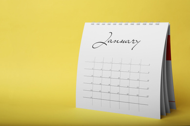Photo of Paper calendar on yellow background, space for text. Planning concept