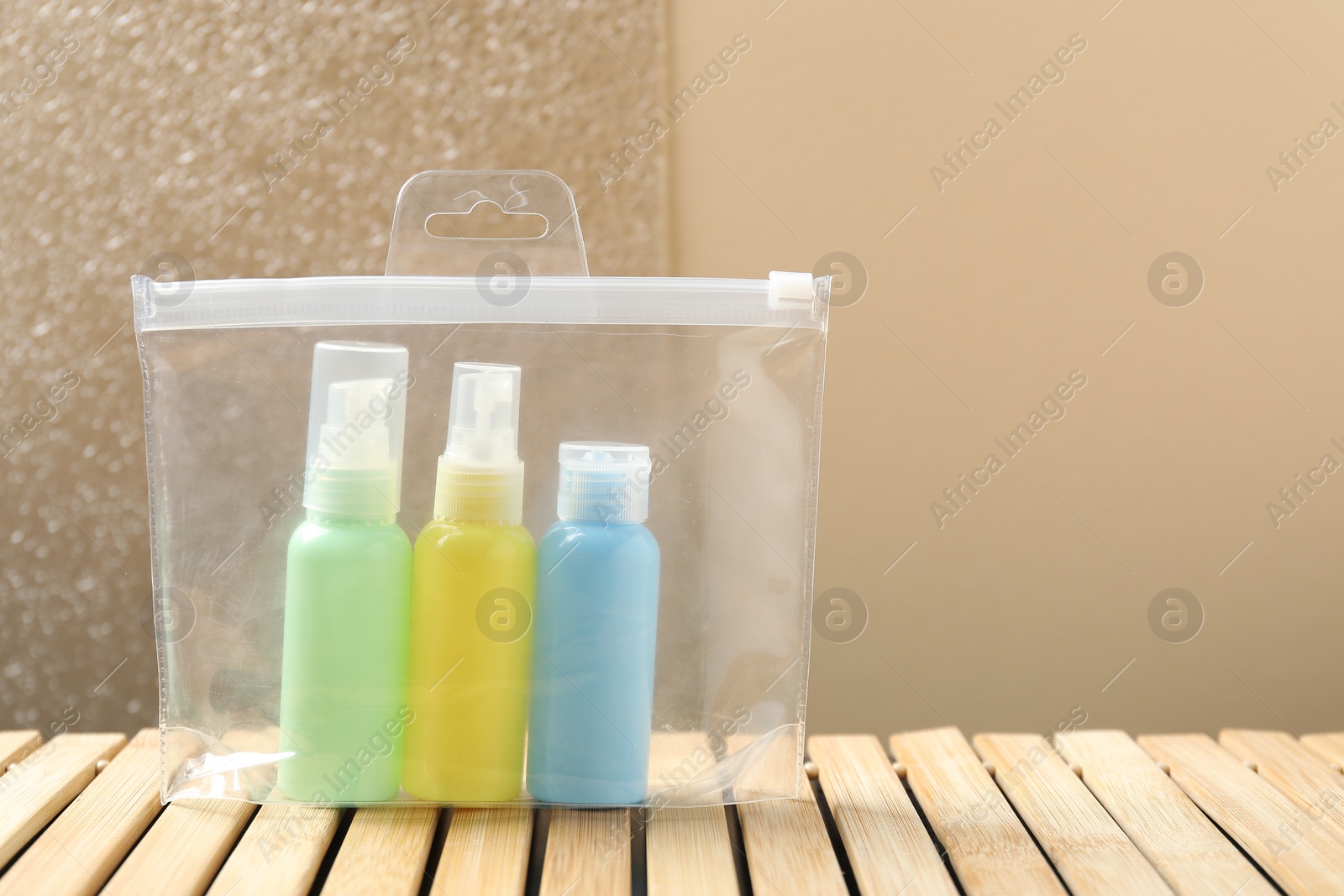 Photo of Cosmetic travel kit in plastic bag on wooden table, space for text. Bath accessories