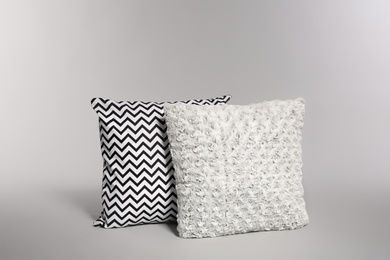 Photo of Two stylish decorative pillows on light background