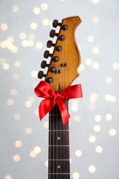 Photo of Guitar with red bow on light background. Christmas music