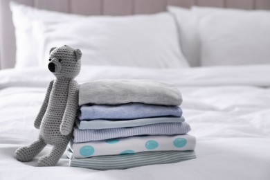 Photo of Stack of clean baby's clothes and toy on bed