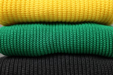 Photo of Stack of casual warm sweaters as background, closeup view