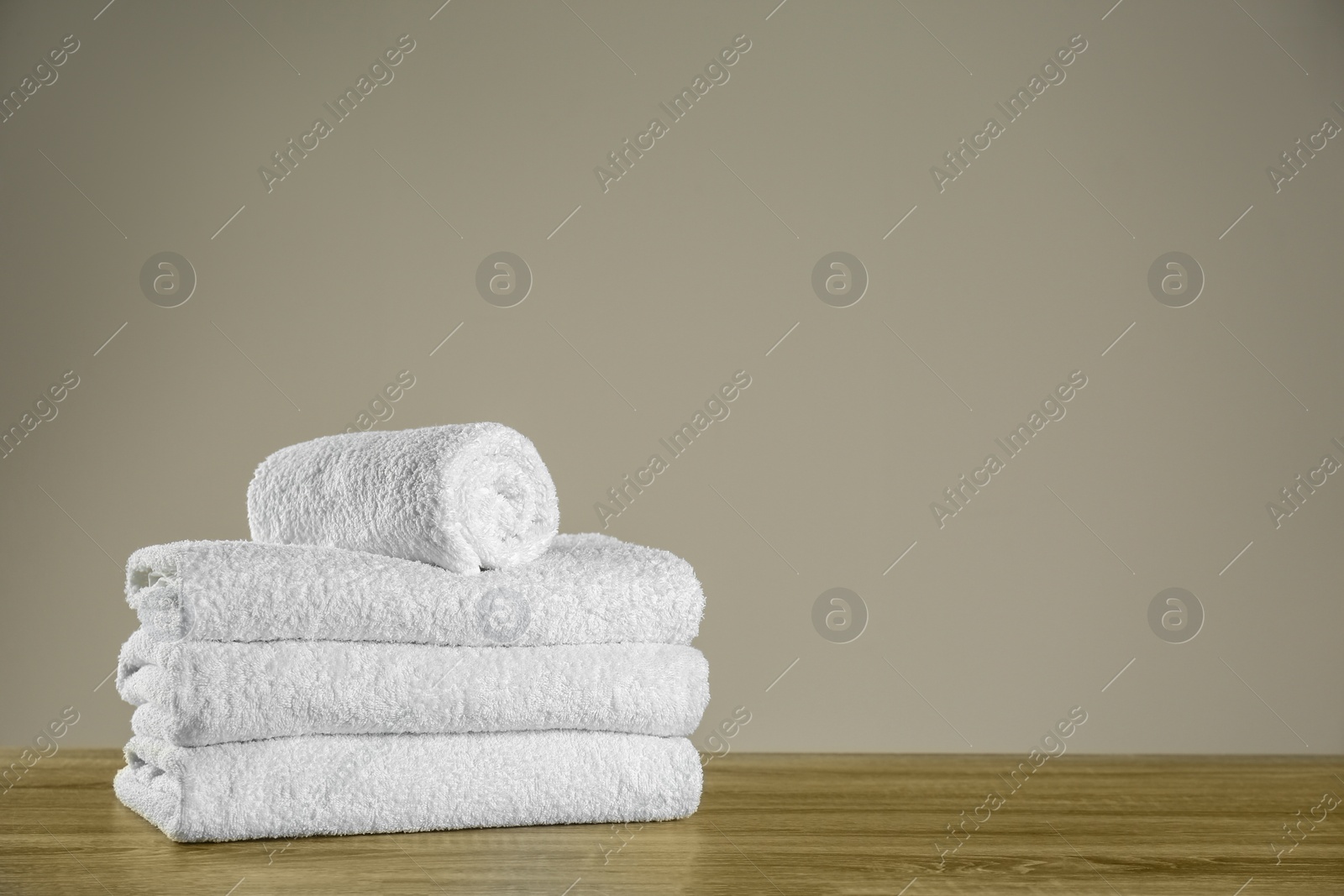 Photo of Clean bath towels on wooden table. Space for text