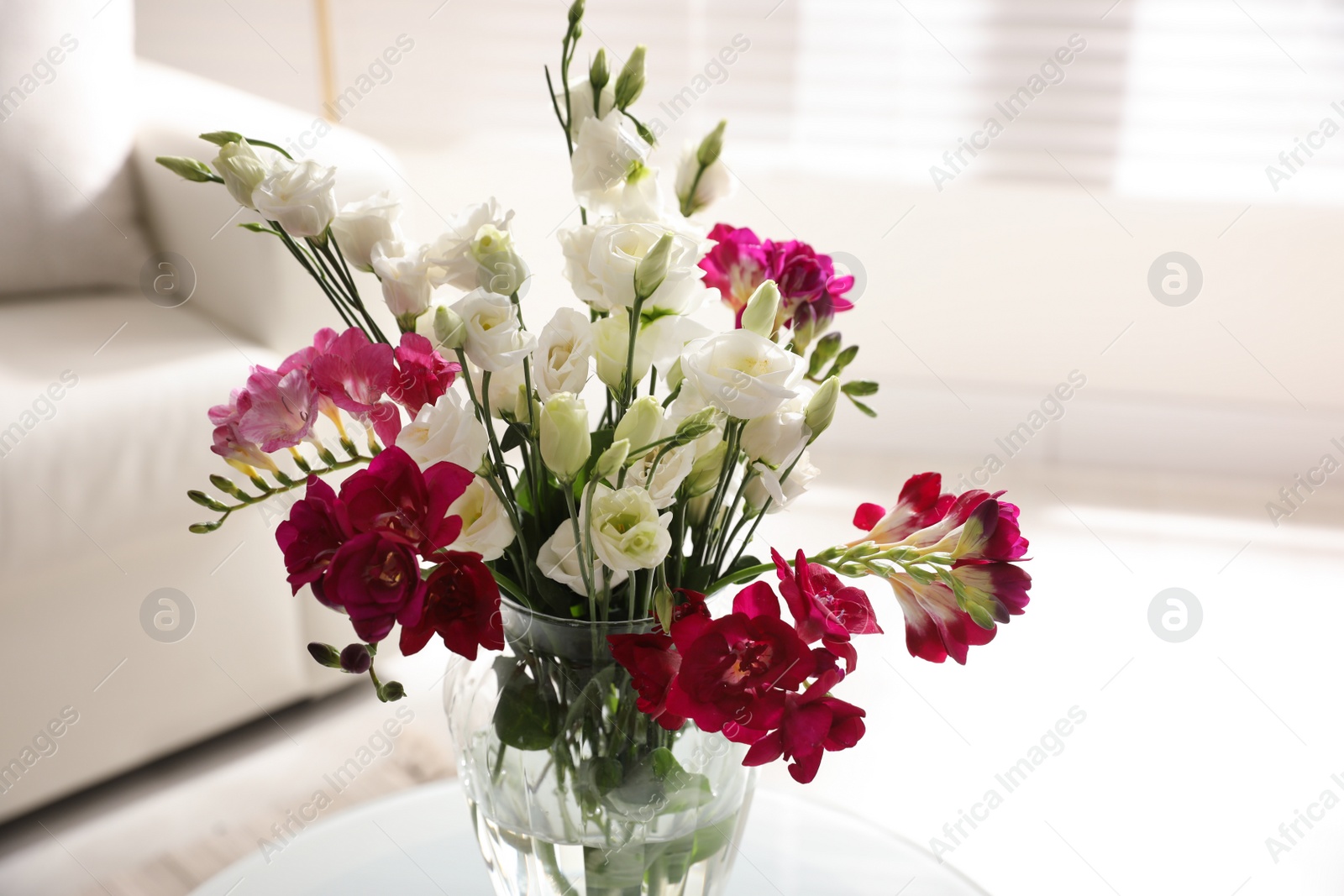 Photo of Beautiful bouquet with spring freesia flowers in light room, closeup