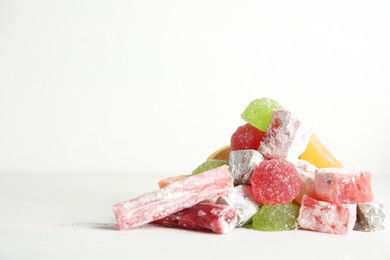 Delicious colorful candies on white table. Space for text