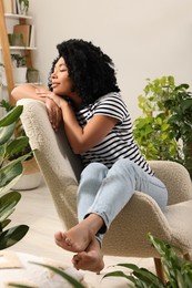 Woman relaxing in armchair surrounded by beautiful houseplants at home