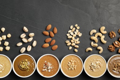 Tasty nut butters in bowls and raw nuts on black table, flat lay